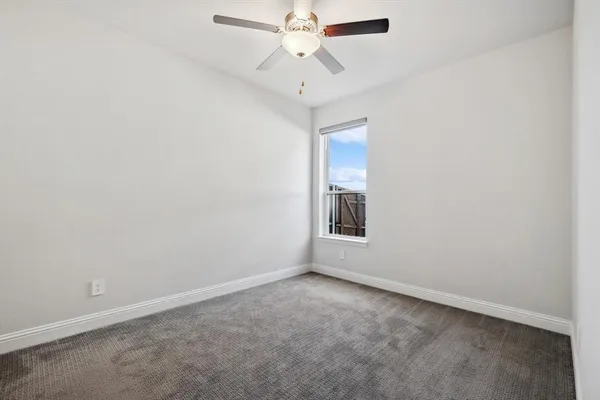 an empty room with a chandelier fan and windows