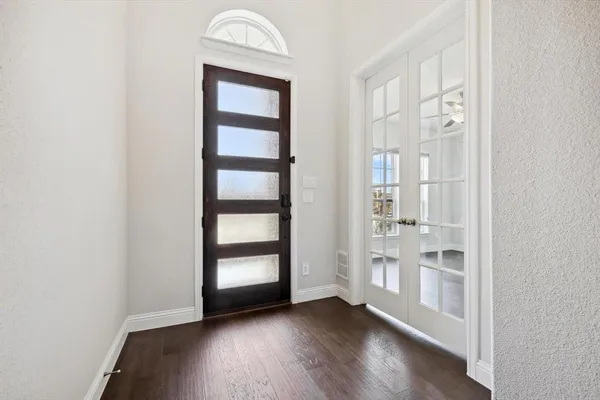 an empty room with wooden floor closet and windows