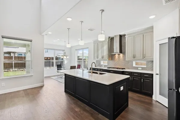 a kitchen with stainless steel appliances granite countertop a sink a stove and a wooden floor