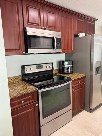 a kitchen with granite countertop a sink a stove and a wooden cabinets