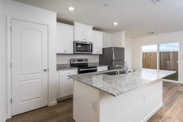 a kitchen with kitchen island granite countertop a sink a counter top space appliances and cabinets