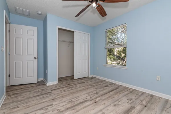 a view of empty room with wooden floor and fan