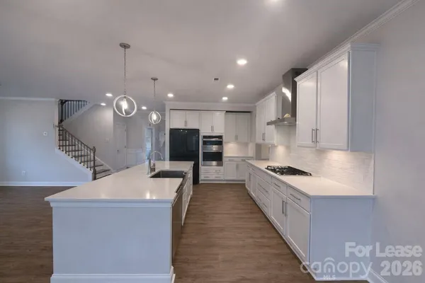 a large kitchen with stainless steel appliances kitchen island a large counter top a sink a stove and a refrigerator