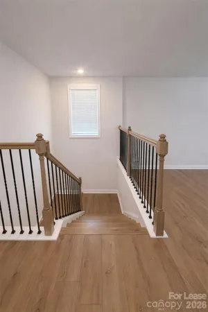 a view of a hallway with wooden floor and stairs