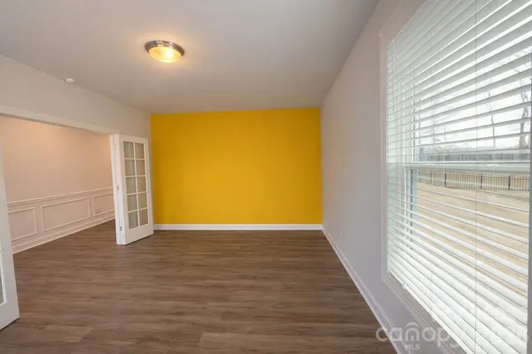 a view of an empty room with wooden floor and a window