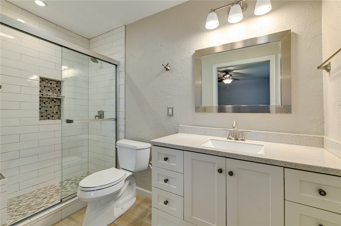 901 Valley View Drive Austin, TX 78733 - Photo 13 of 25 a bathroom with a toilet a sink a glass door a shower a vanity and mirror