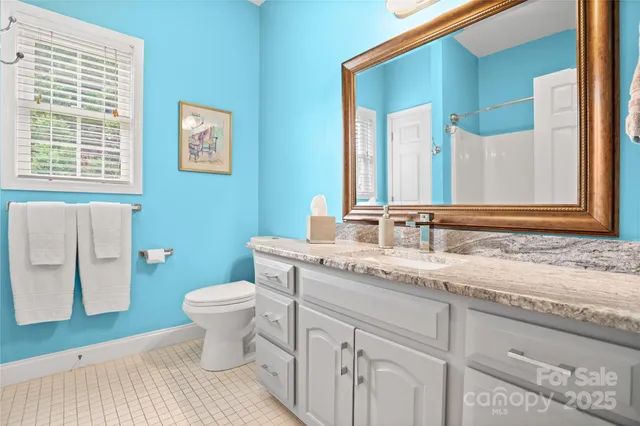 a bathroom with a granite countertop double vanity sink a mirror and a toilet