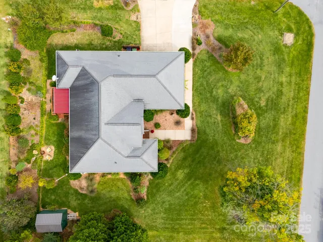 an aerial view of a house with swimming pool and large trees