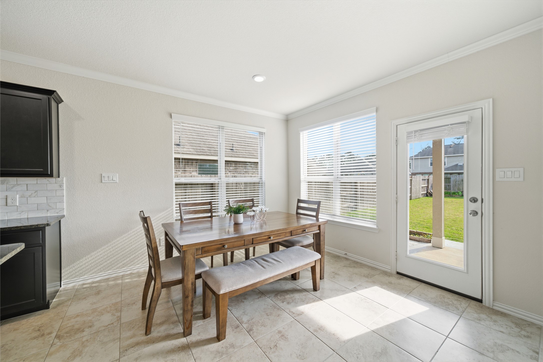 4335 Tawny Timber Drive Spring, TX 77386 - Photo 15 of 42 Bright dining area with large windows, tiled floors, and a door leading to the backyard. Features a wooden table with chairs and a bench, adjacent to the kitchen. Ideal for family meals and entertaining.