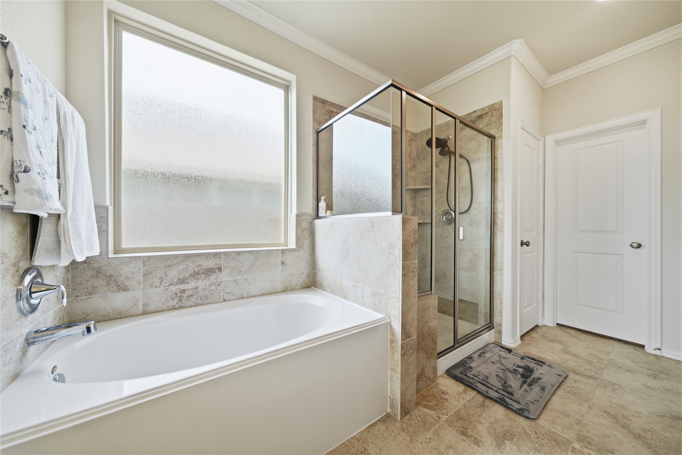 4335 Tawny Timber Drive Spring, TX 77386 - Photo 20 of 42 This bathroom features a spacious layout with a large soaking tub and a separate glass-enclosed shower. The neutral-toned tiles and frosted window provide a bright and serene atmosphere.