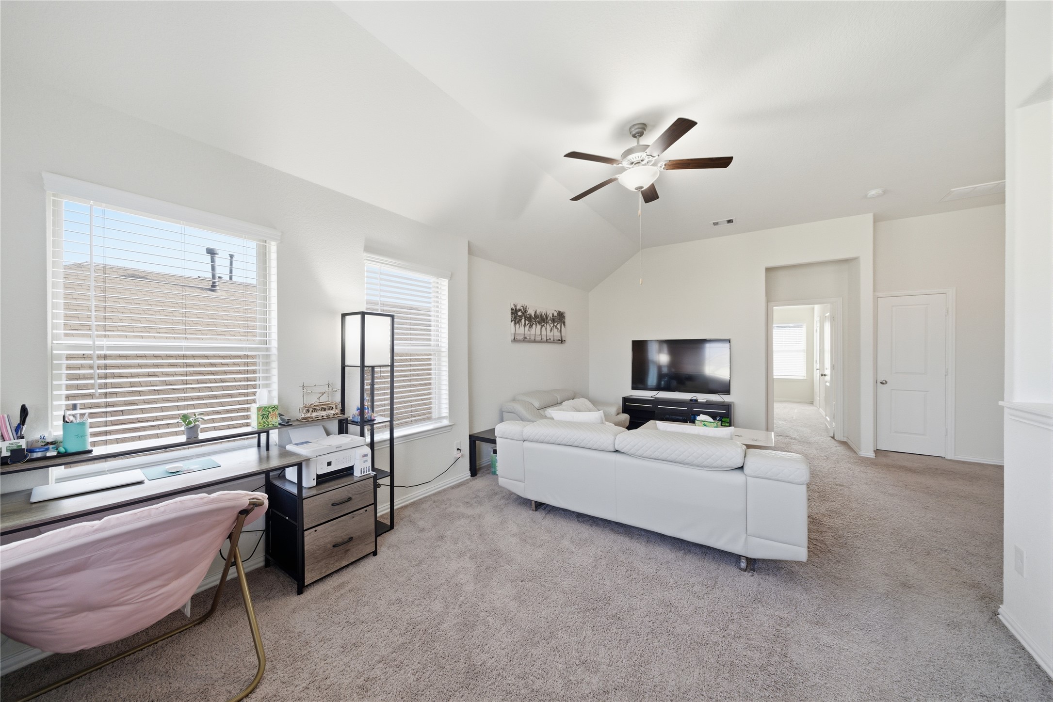 4335 Tawny Timber Drive Spring, TX 77386 - Photo 25 of 42 This room features a cozy carpeted space with abundant natural light, a ceiling fan, and a versatile layout. It includes a comfortable seating area with a TV, a work desk by the window, and access to an adjacent room, creating a perfect blend of relaxation and functionality.