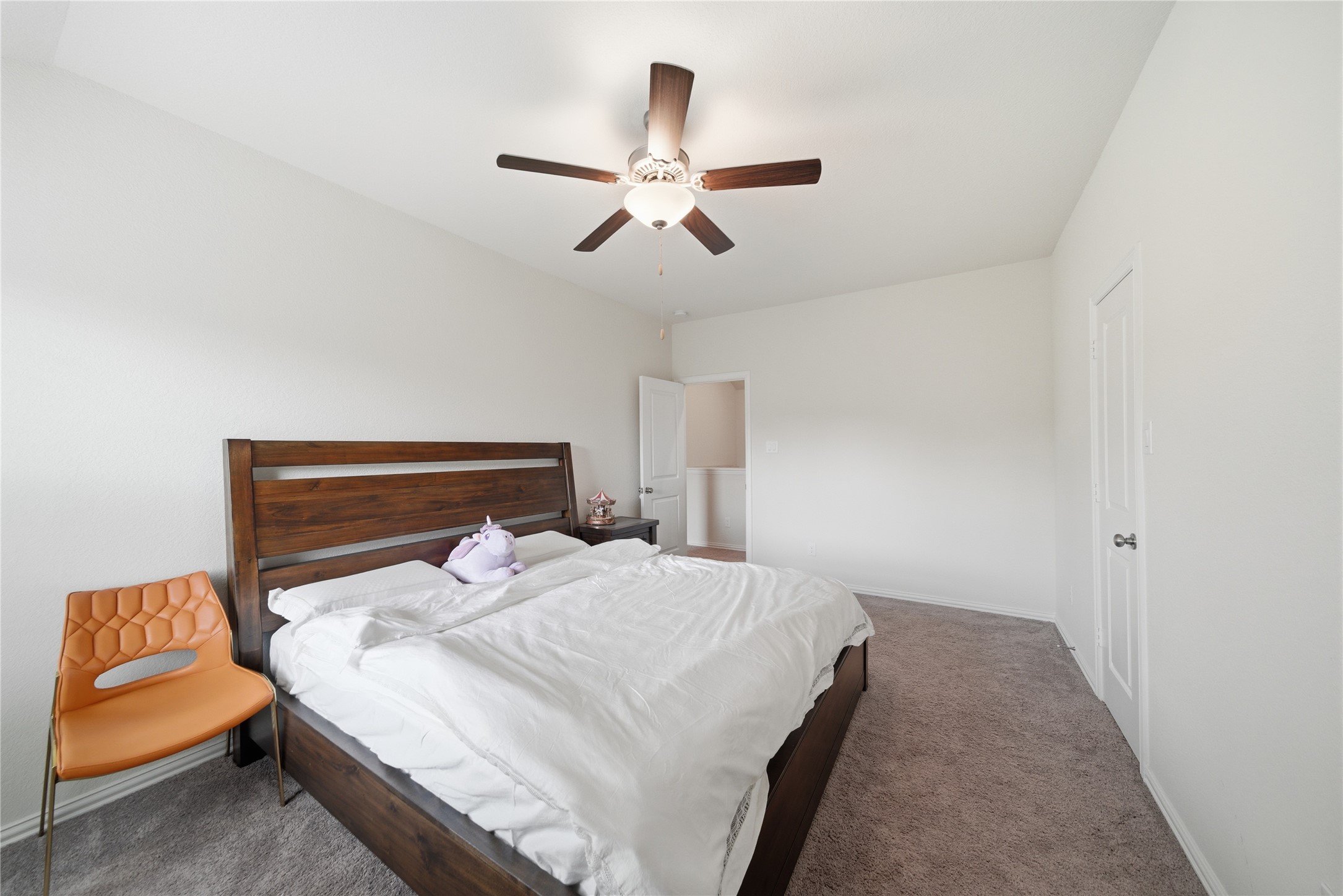 4335 Tawny Timber Drive Spring, TX 77386 - Photo 32 of 42 Bright, spacious bedroom with neutral walls and carpeted flooring. Features a ceiling fan, wooden bed frame, and a modern chair. Ample natural light enhances the cozy ambiance.