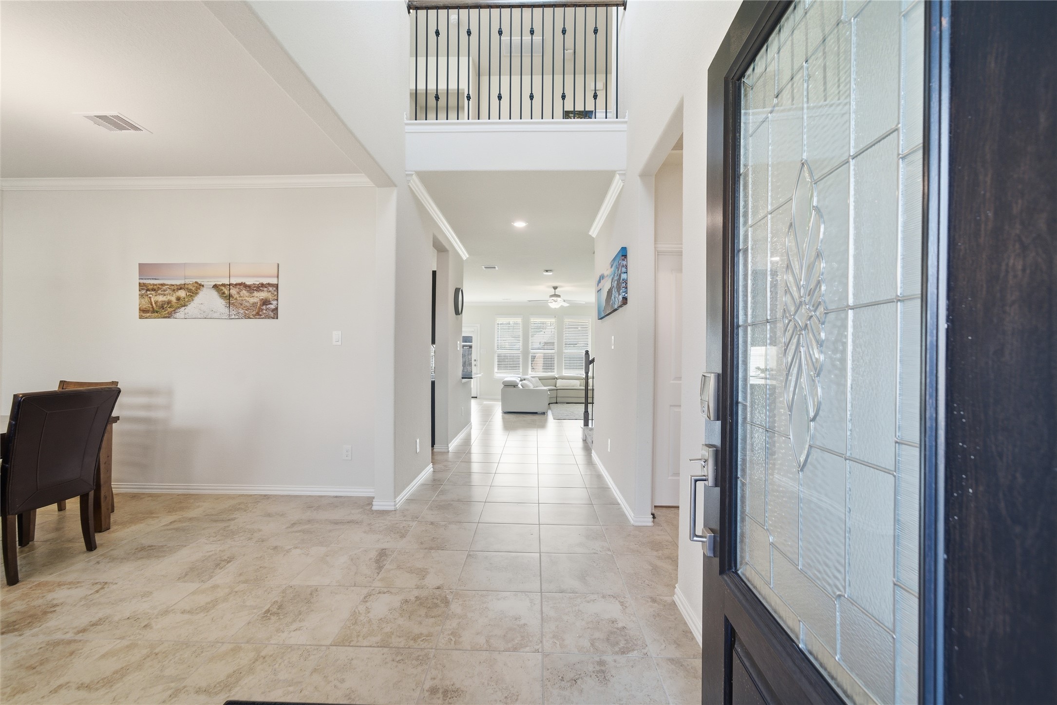 4335 Tawny Timber Drive Spring, TX 77386 - Photo 4 of 42 This photo showcases a welcoming entryway with a view into an open-concept living area. The space features tiled flooring, high ceilings, and abundant natural light. A staircase with a decorative railing is visible, adding elegance to the modern design.