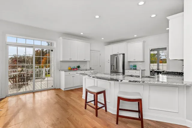 a kitchen with stainless steel appliances granite countertop a stove top oven a sink dishwasher and white cabinets with wooden floor