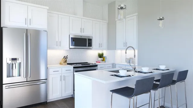 a kitchen with stainless steel appliances a stove a refrigerator and white cabinets with wooden floor