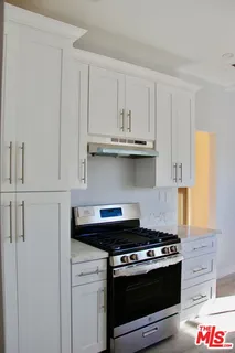 a kitchen with stainless steel appliances granite countertop white cabinets and a stove a oven with white countertops