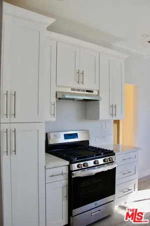 a kitchen with stainless steel appliances granite countertop white cabinets and a stove a oven with white countertops