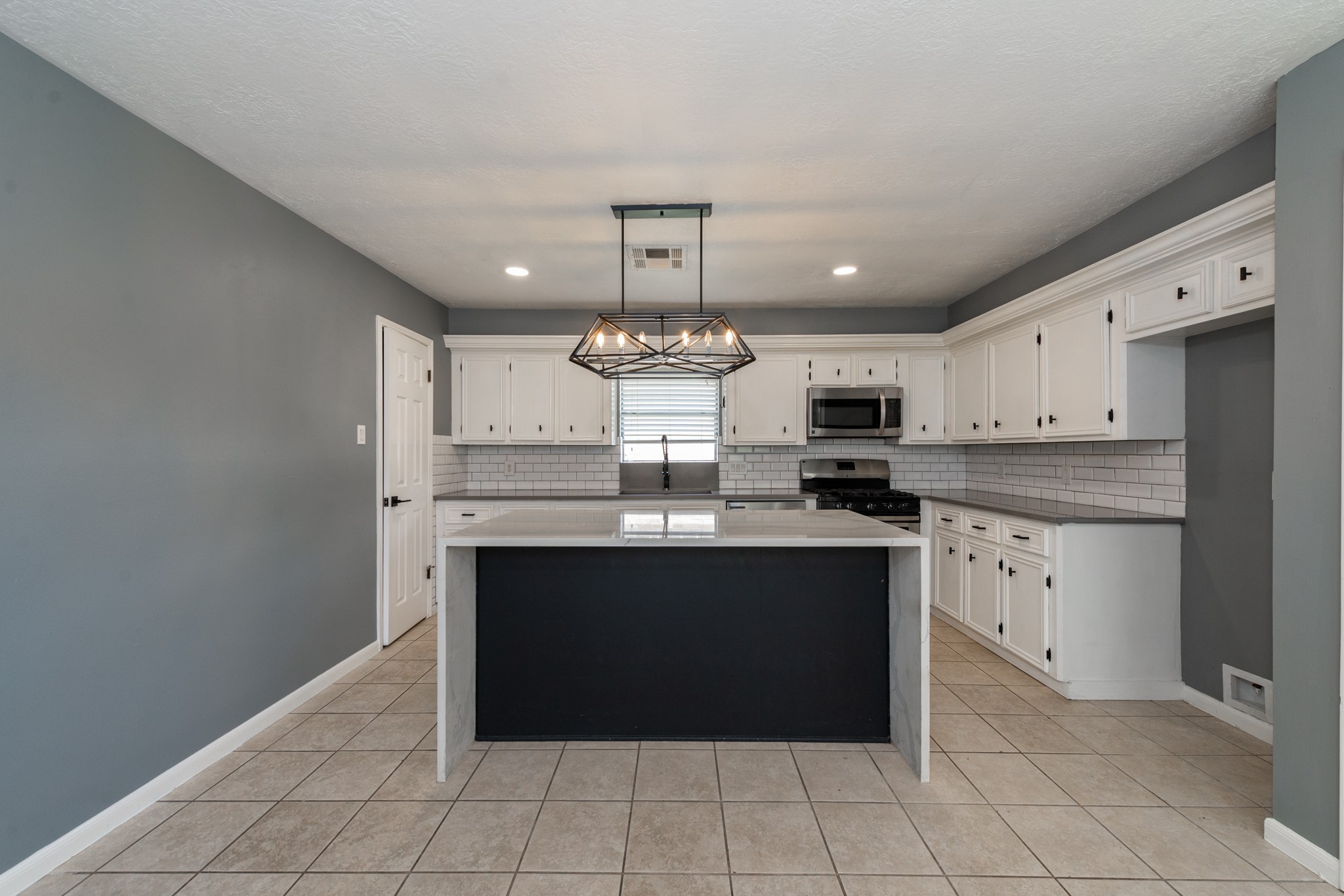 1022 White Sands Road Katy, TX 77450 - Photo 11 of 27 Kitchen island with upgraded lighting and appliances showcasing the quartz waterfall island.