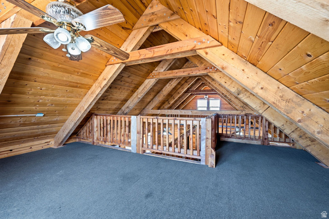 10937 South County Road, Unit 29 Duchesne, UT 84021 - Photo 20 of 41 Loft space featuring exposed wood beams, wood paneling, dark carpet, a ceiling fan with integrated lighting, and a window providing natural illumination