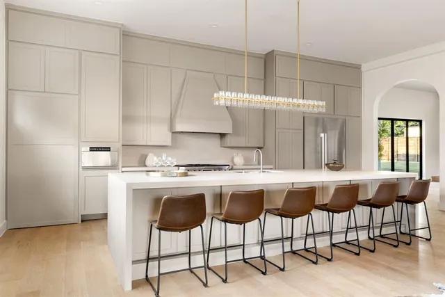 a kitchen with a stove a refrigerator and chairs