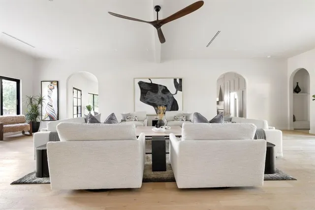 a living room with couches and kitchen view with wooden floor