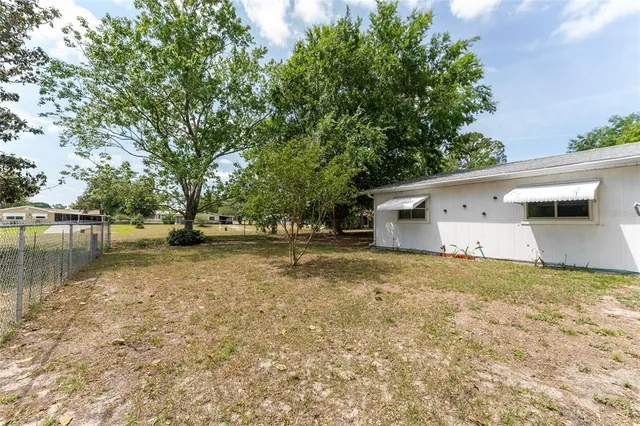 a view of a house with backyard and trees