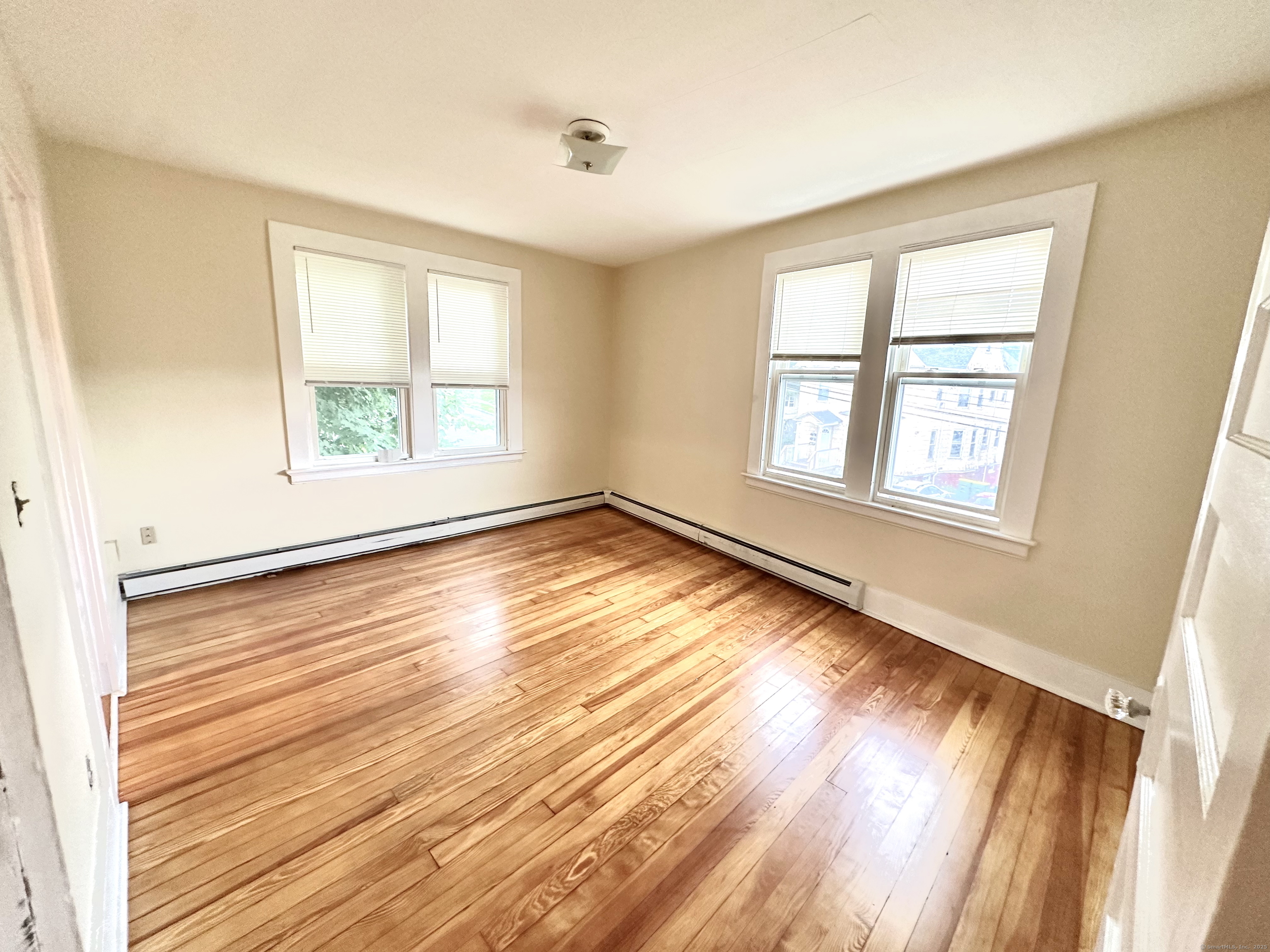 a view of an empty room with wooden floor and a window