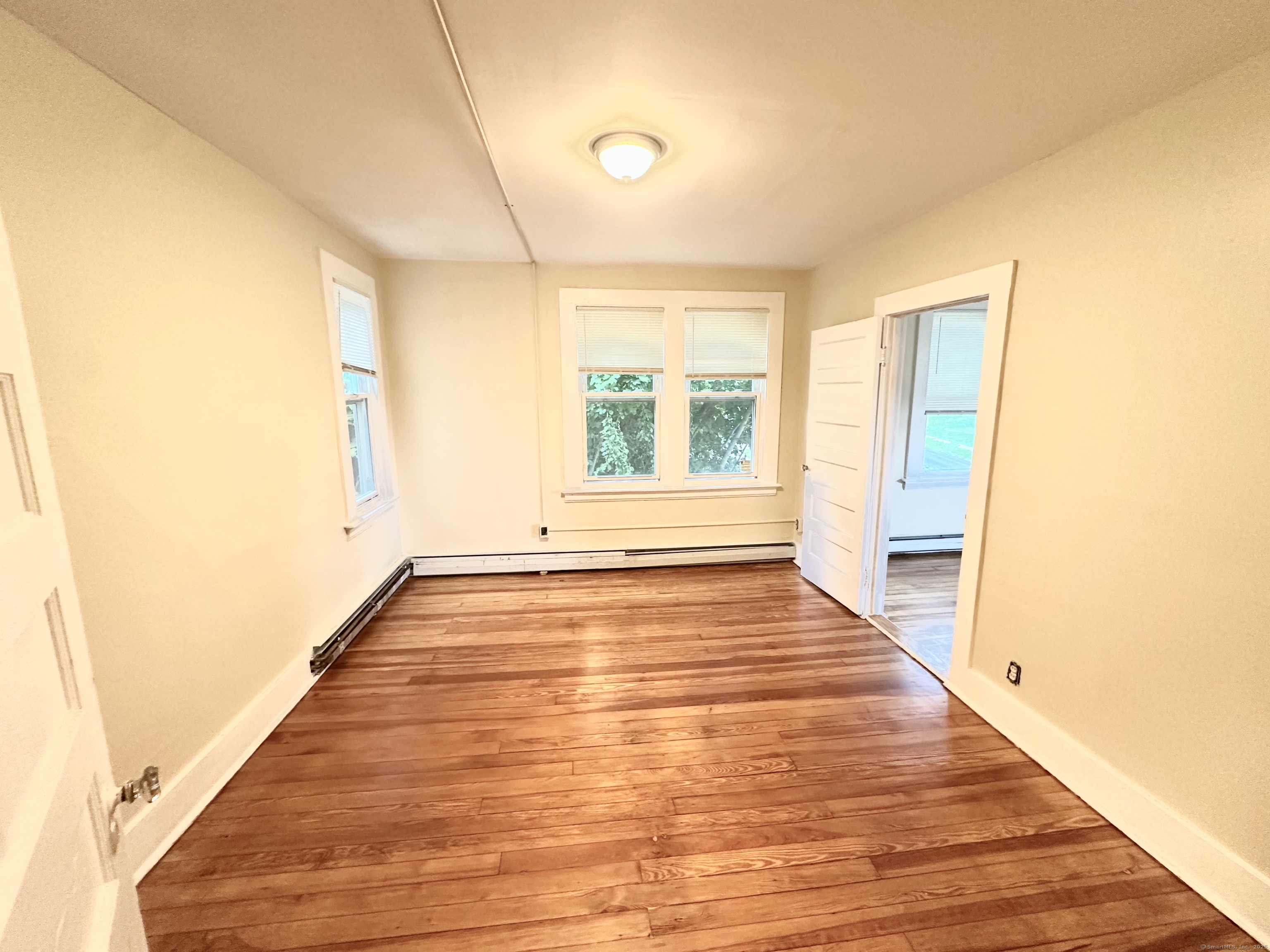 1019 West Main Street, Unit 3R Waterbury, CT 06708 - Photo 6 of 25 a view of an empty room with wooden floor and a window