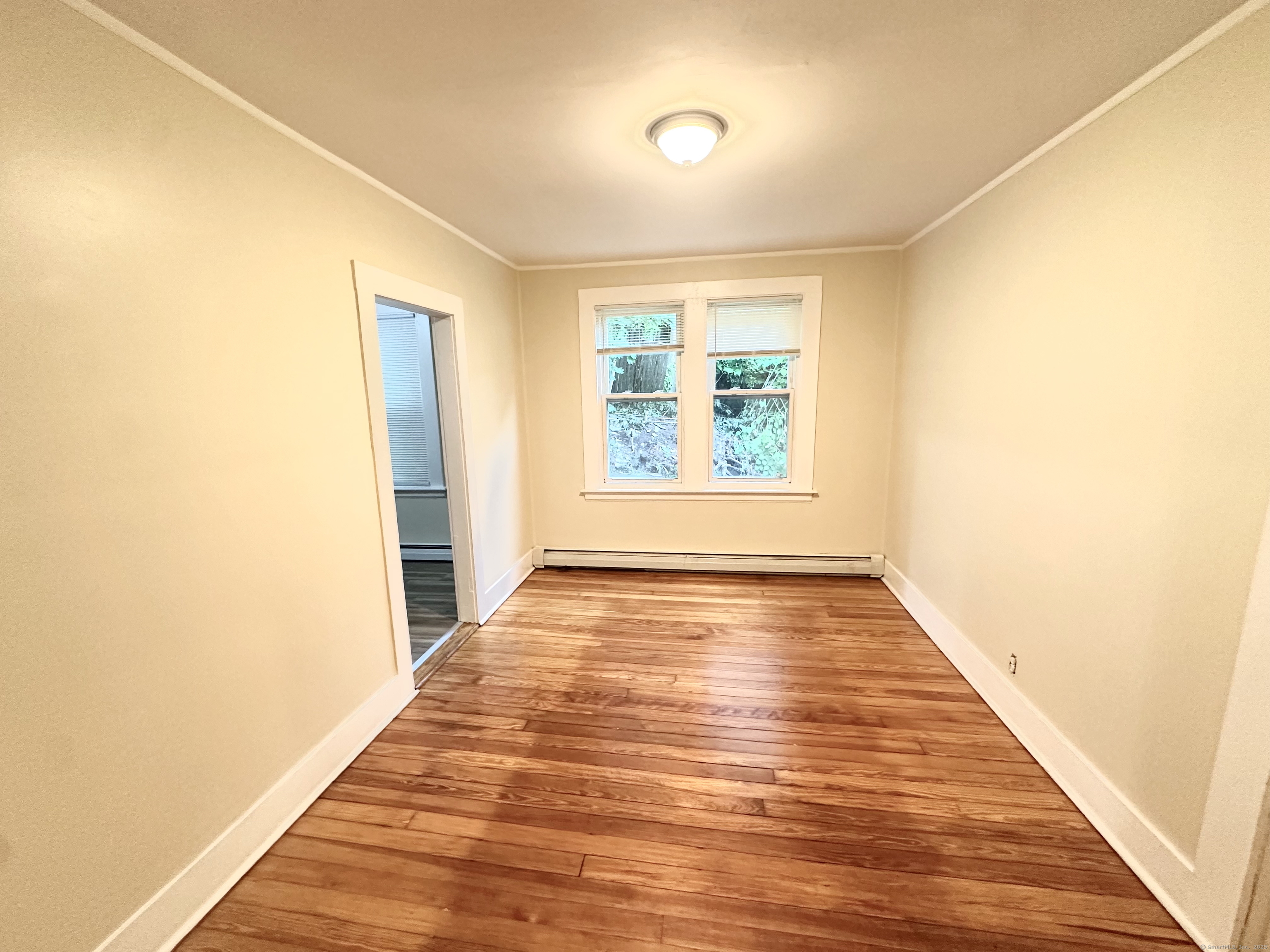 1019 West Main Street, Unit 3R Waterbury, CT 06708 - Photo 9 of 25 a view of an empty room with wooden floor and a window