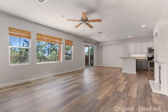 a view of an empty room with a window and wooden floor