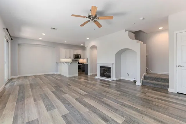 a view of empty room with kitchen and fireplace