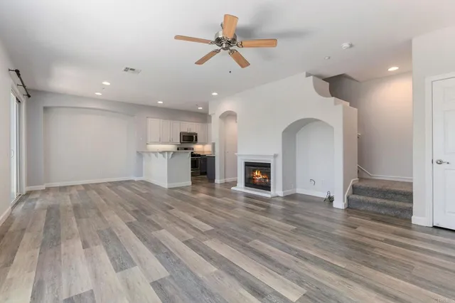 a view of empty room with kitchen and fireplace