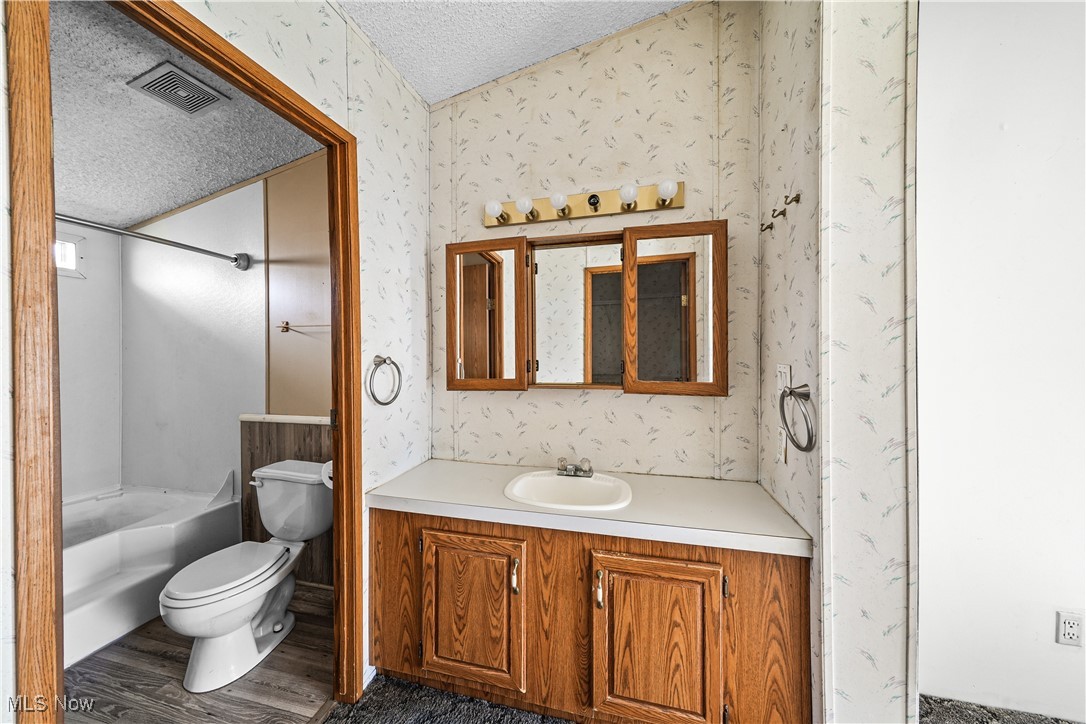 3792 Selnik Road Kent, OH 44240 - Photo 14 of 39 Full bath featuring wallpapered walls, visible vents, toilet, a textured ceiling, and vanity