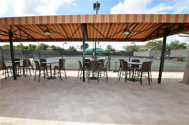 a view of patio with table and chairs under an umbrella with a barbeque