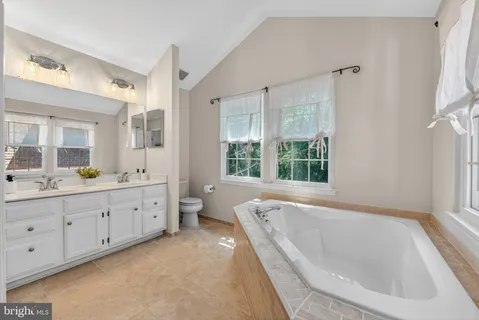a bathroom with a granite countertop tub sink and mirror