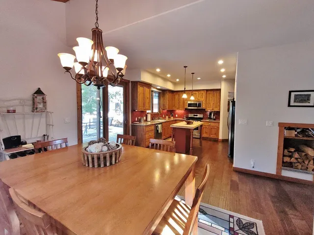 a view of a dining room and livingroom with furniture wooden floor a chandelier