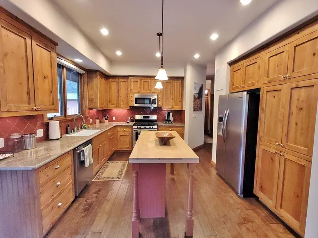 a large kitchen with stainless steel appliances sink refrigerator and cabinets