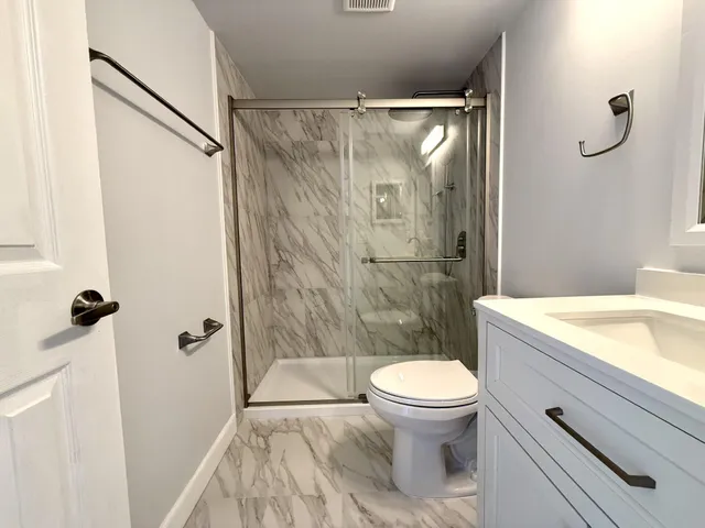 a bathroom with a granite countertop sink toilet and shower