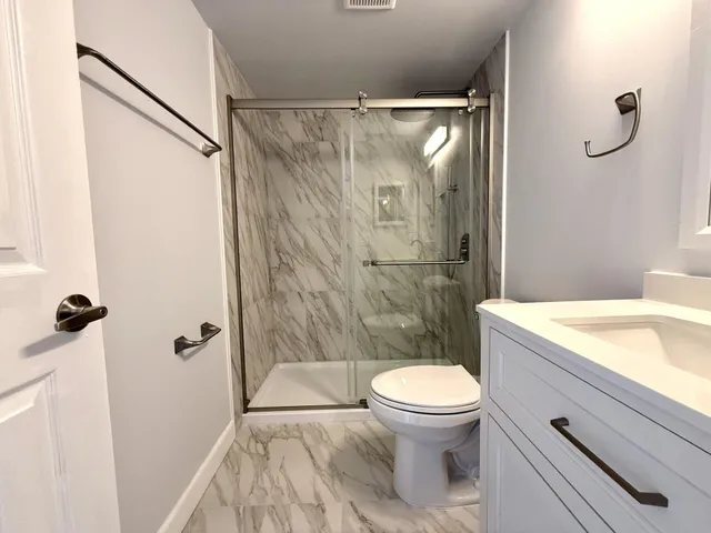 a bathroom with a granite countertop sink toilet and shower