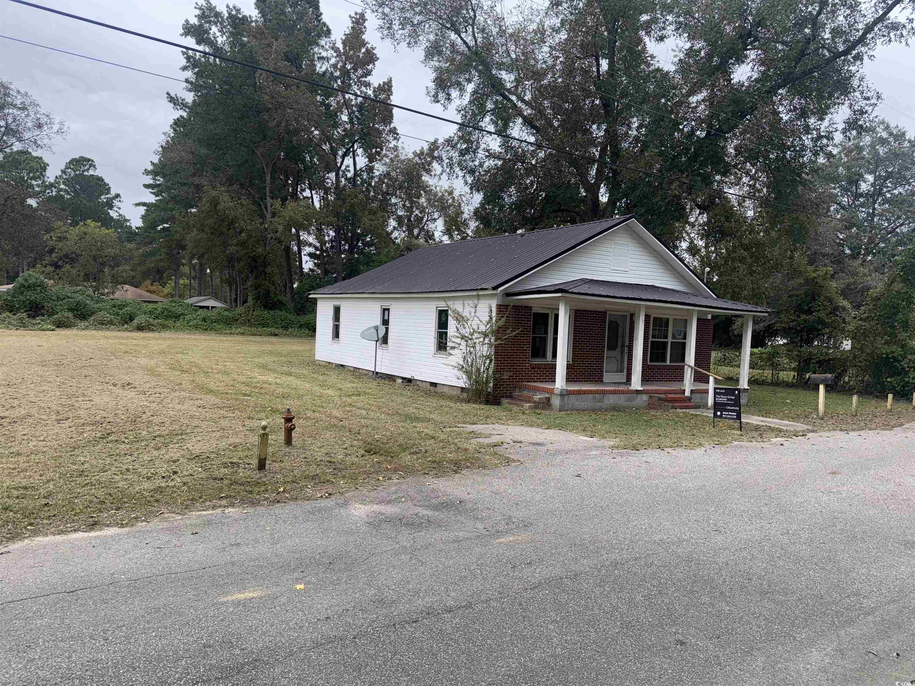 106 Raeford Street Mullins, SC 29574 - Photo 2 of 15 Bungalow with a porch, crawl space, a front yard, a metal roof, and view of wooded area