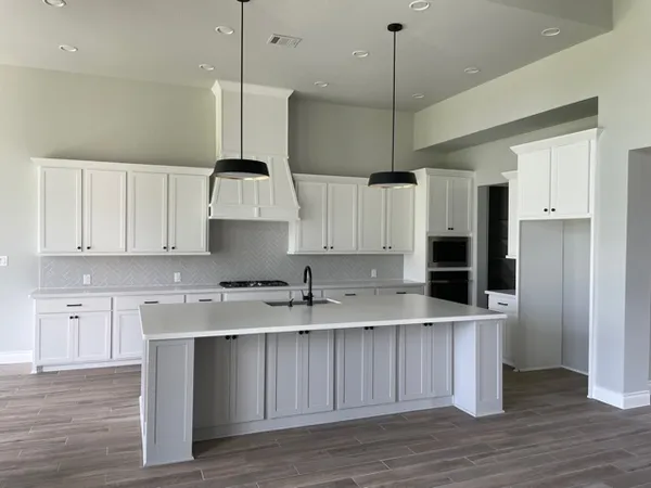 a kitchen with stainless steel appliances granite countertop a sink a stove a refrigerator and island with wooden floor