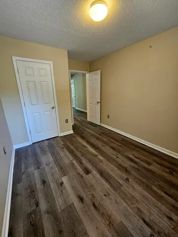 a view of an empty room with wooden floor and closet