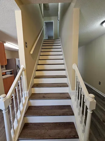 a view of staircase with wooden floor and white walls