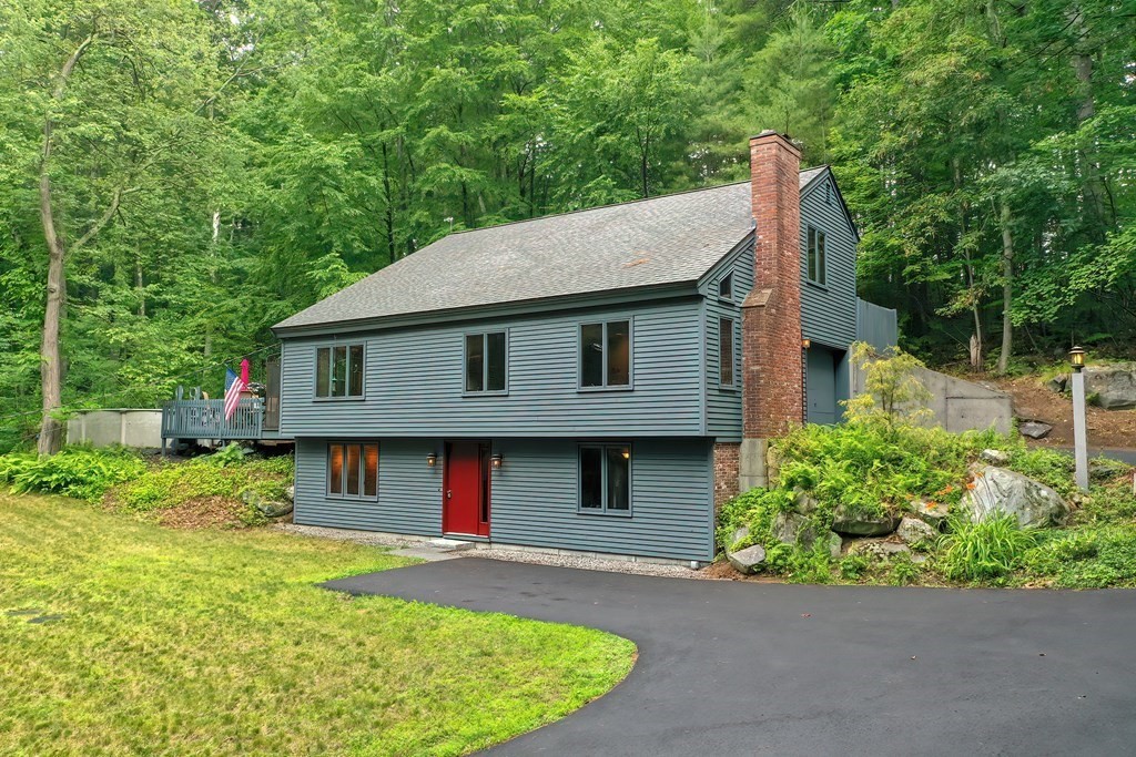 a view of a house with a yard plants and large tree