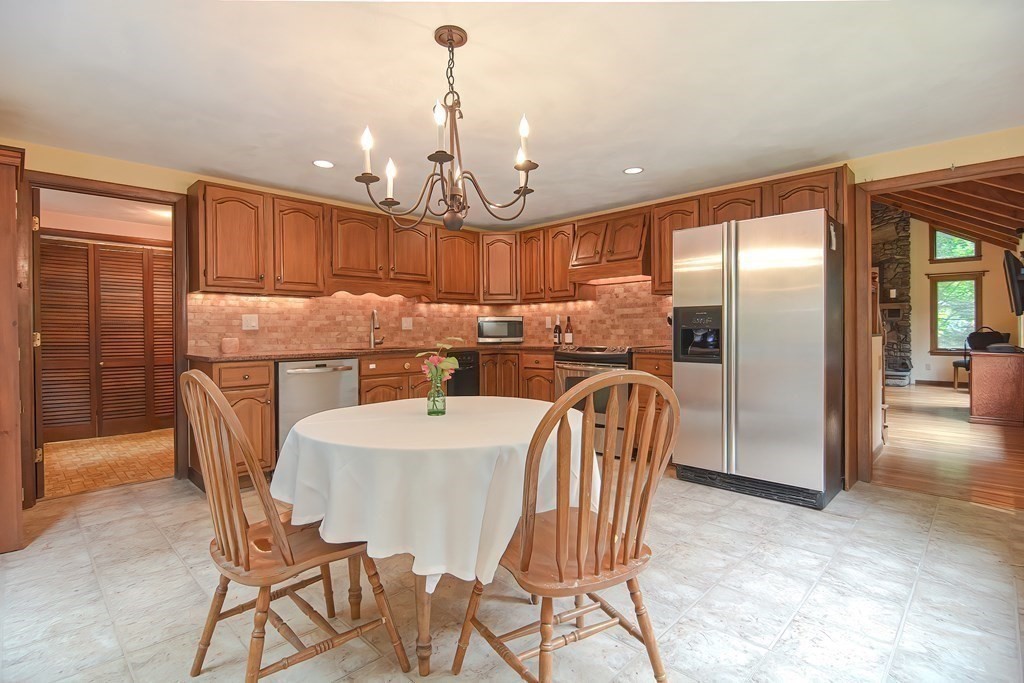 202 Boxboro Road Stow, MA 01775 - Photo 11 of 40 a kitchen with stainless steel appliances granite countertop a refrigerator a stove a sink a dining table and chairs with wooden floor