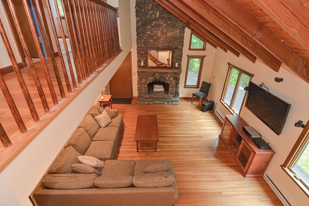 202 Boxboro Road Stow, MA 01775 - Photo 19 of 40 a living room with couches a flat screen tv and a fireplace with wooden floor
