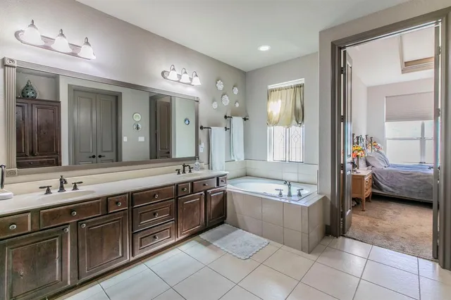 a spacious bathroom with a tub a double vanity sink and a mirror