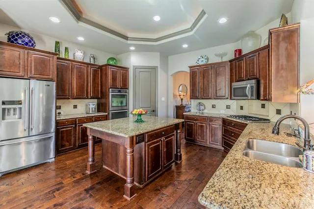 a kitchen with kitchen island granite countertop a sink stove and refrigerator