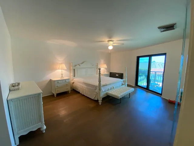 a spacious bedroom with a bed and wooden floor