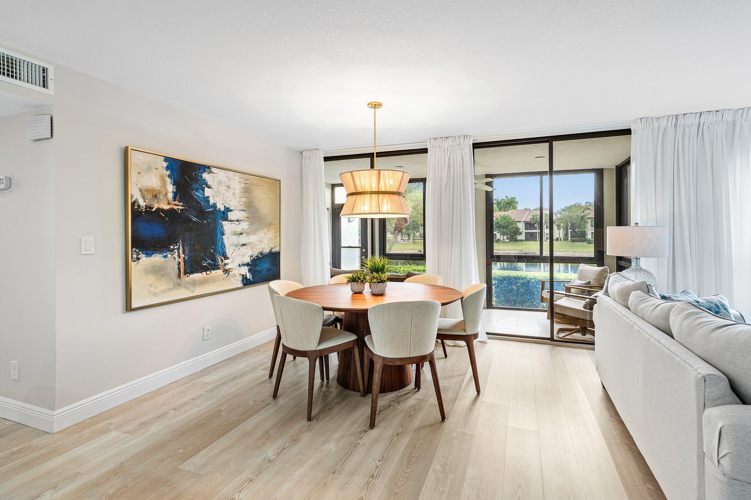 7918 Granada Place, Unit 103 Boca Raton, FL 33433 - Photo 11 of 31 a dining room with wooden floor a chandelier a glass table and chairs